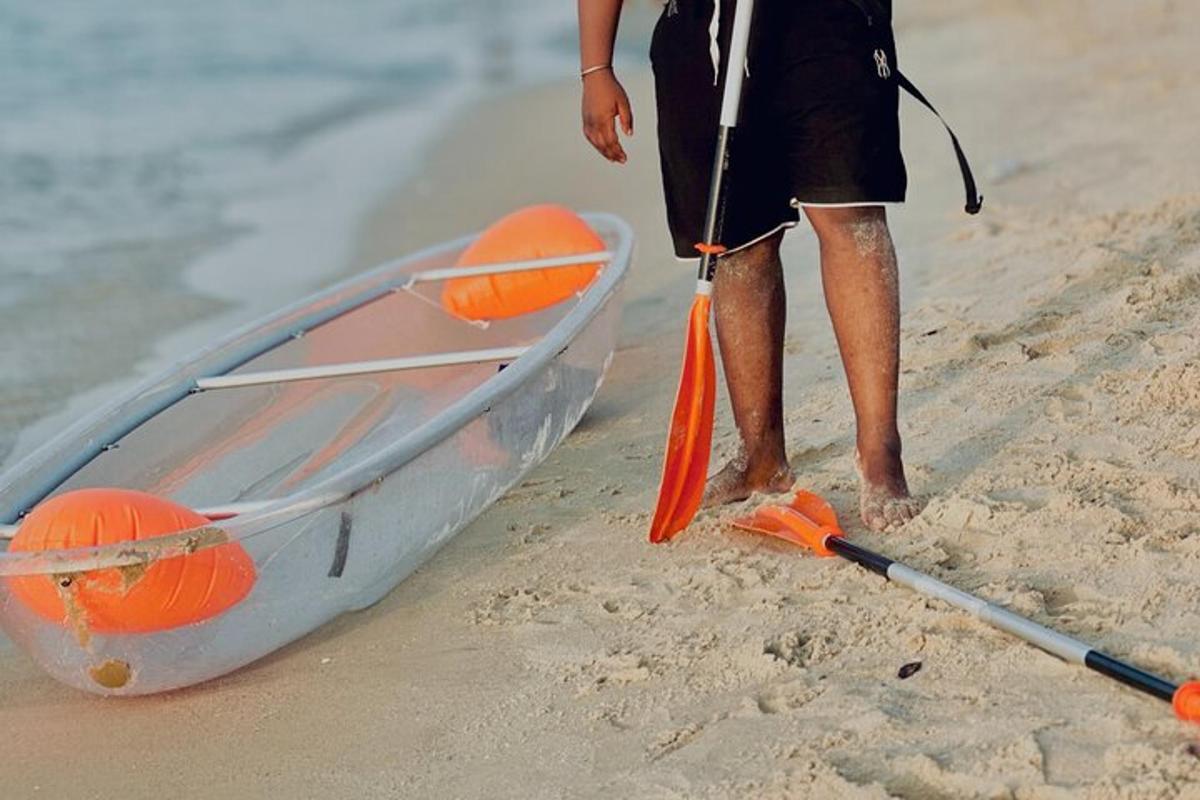 Un hombre de pie junto a un kayak en la playa.