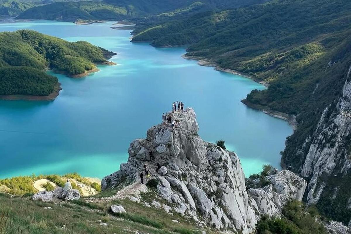 skupina lidí stojící na vrcholu hory s výhledem na jezero