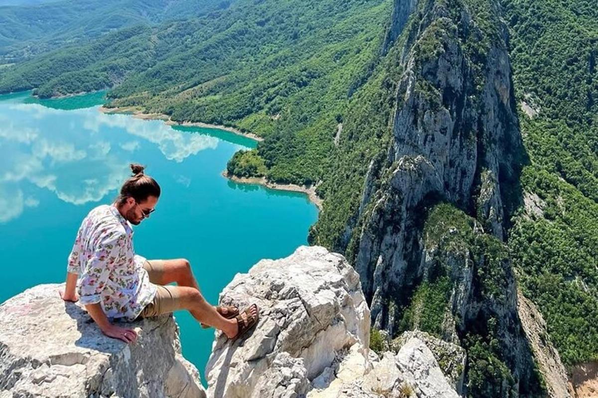 žena sedící na vrcholu hory s výhledem na jezero