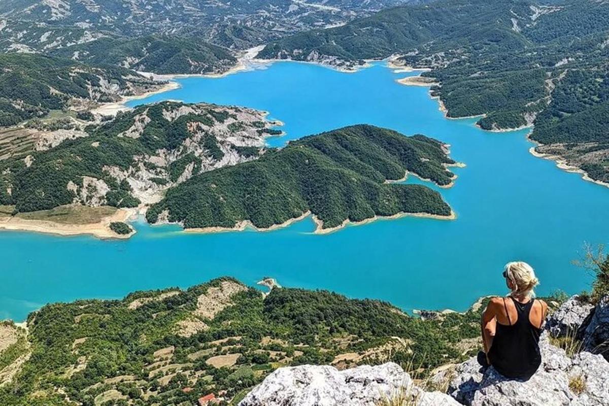 žena sediaca na vrchole hory a pozerajúca sa na jazero