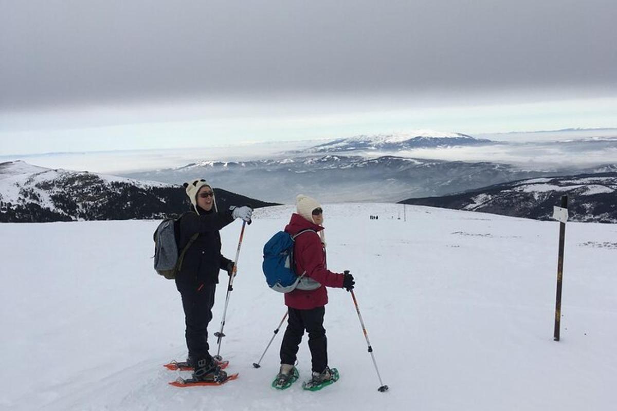 to menn som står på toppen av et snødekt fjell