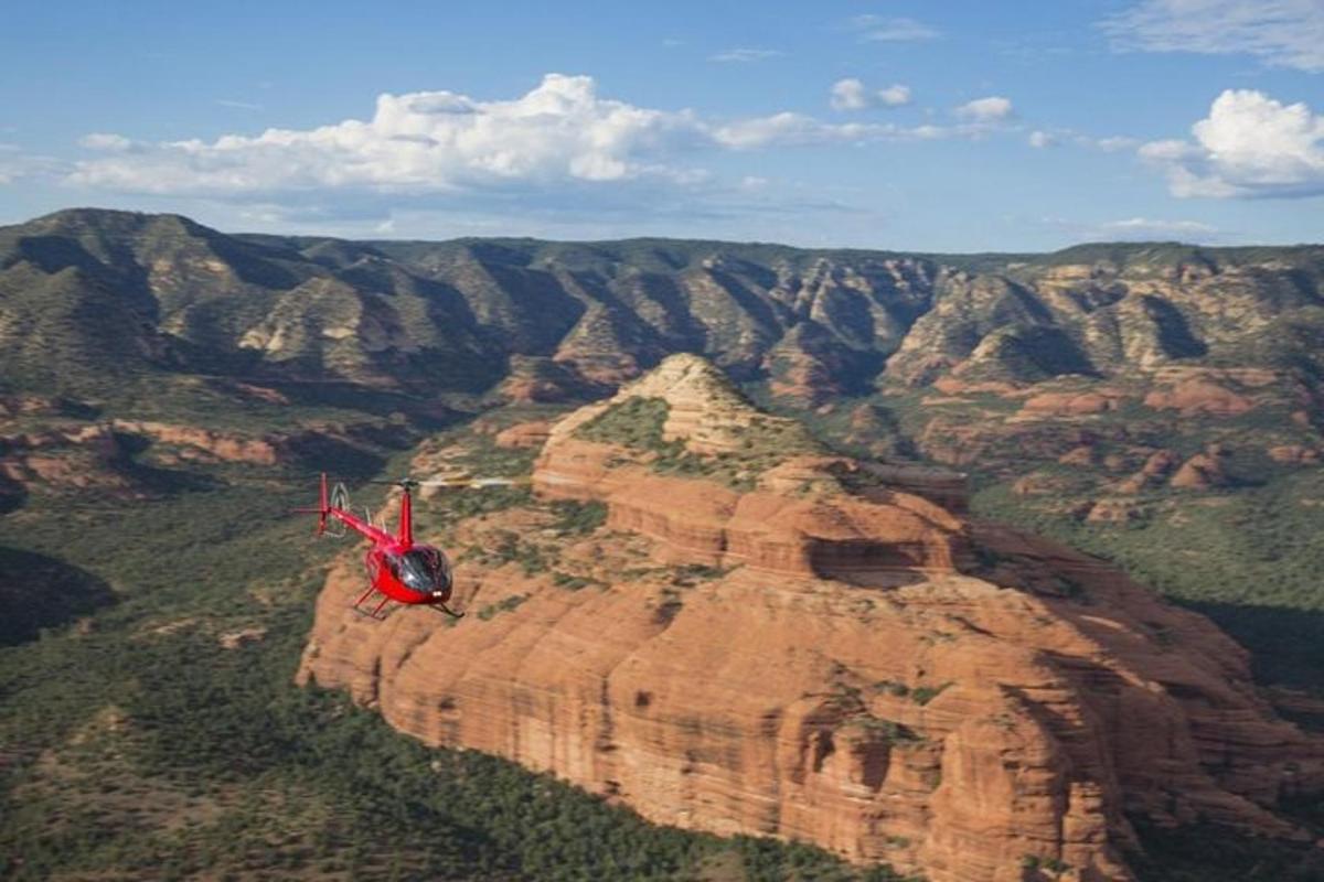 Červený vrtulník letící nad Grand Canyonem