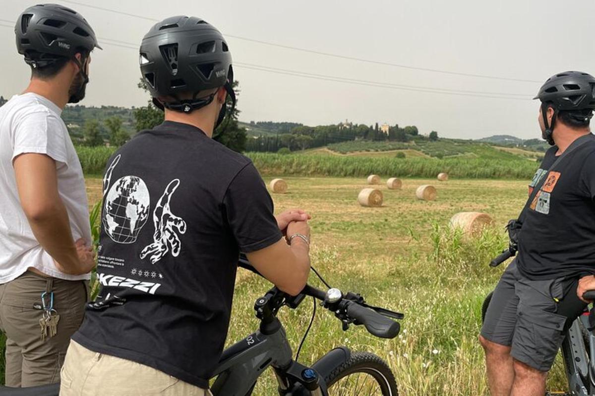 three men wearing helmets standing in a field with a bike