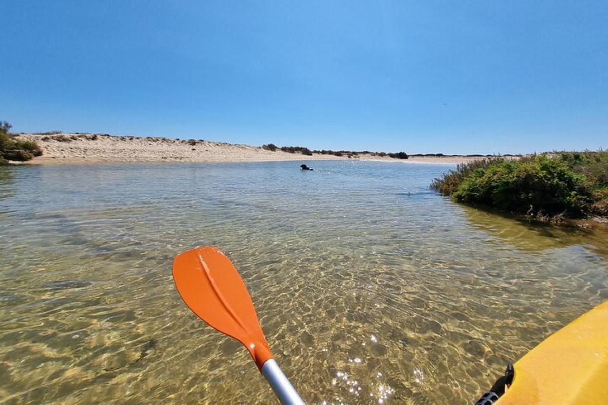 an orange kayak in the water next to a beach