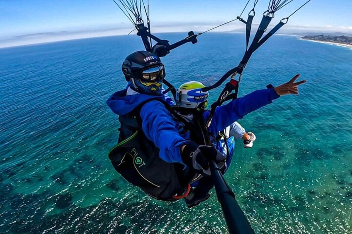 a man and a child riding a parachute over the ocean