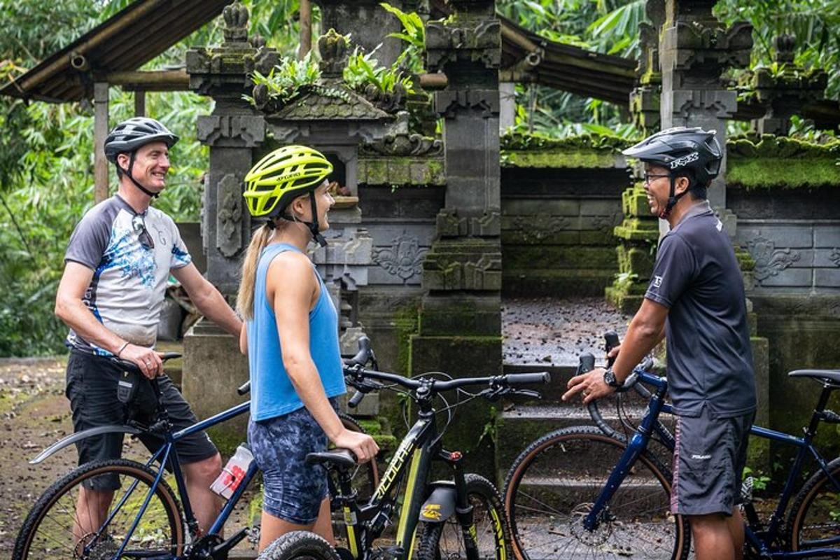 três pessoas usando capacetes em pé ao lado de suas bicicletas