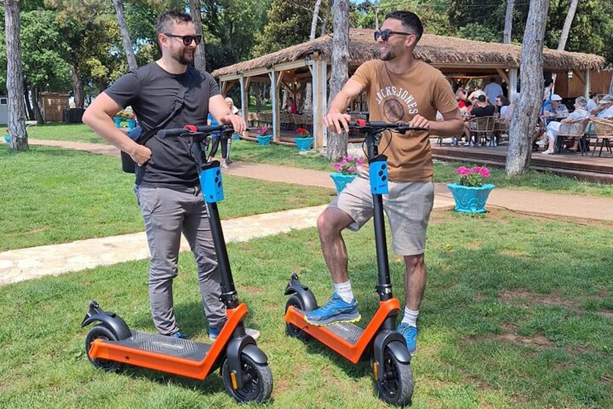 two men are standing on scooters in a park