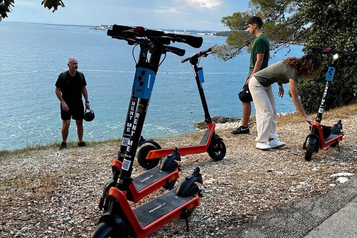 two people standing next to two scooters on the beach