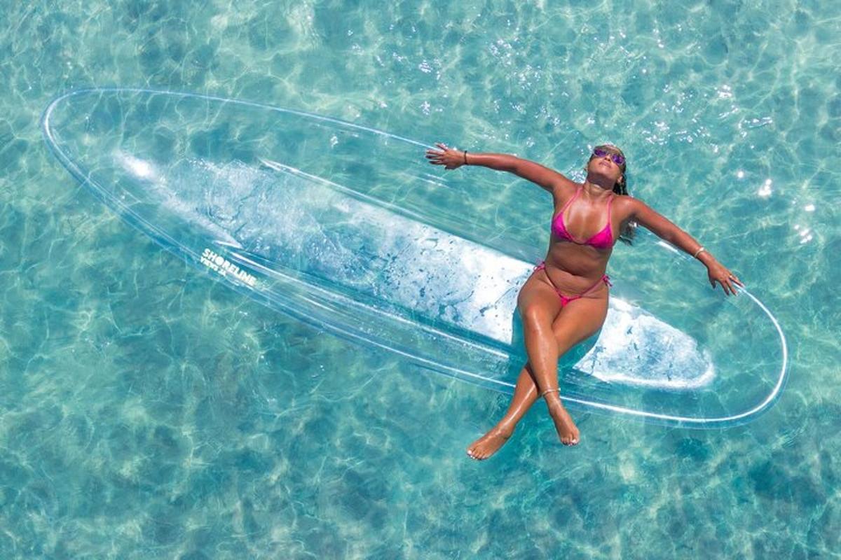 una donna in bikini sdraiata su una tavola da surf in acqua
