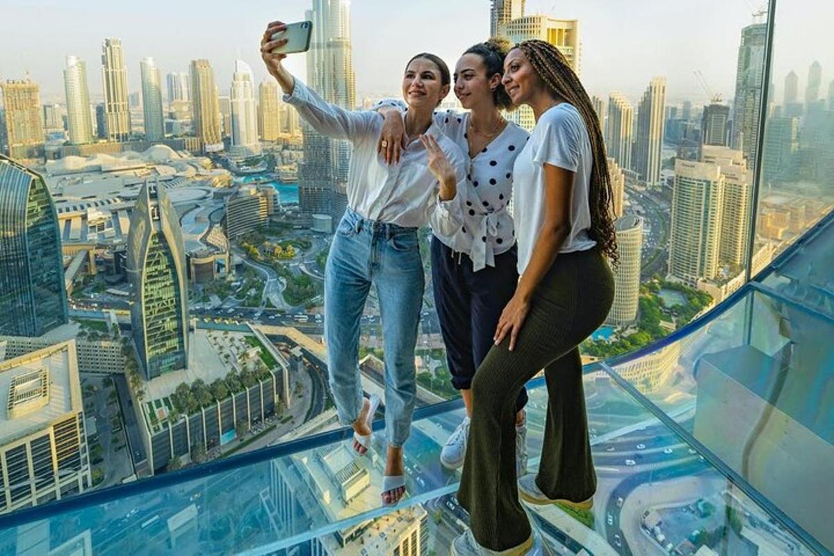 tiga wanita mengambil gambar di atas bangunan pencakar langit