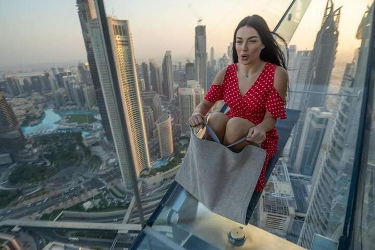 một người phụ nữ mặc váy đỏ đang ngồi trên đỉnh tòa nhà