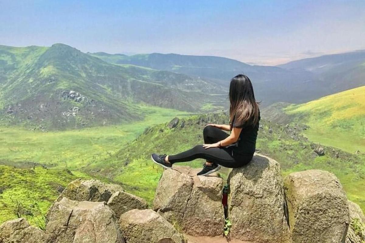 ženska, ki sedi na skali in gleda na dolino