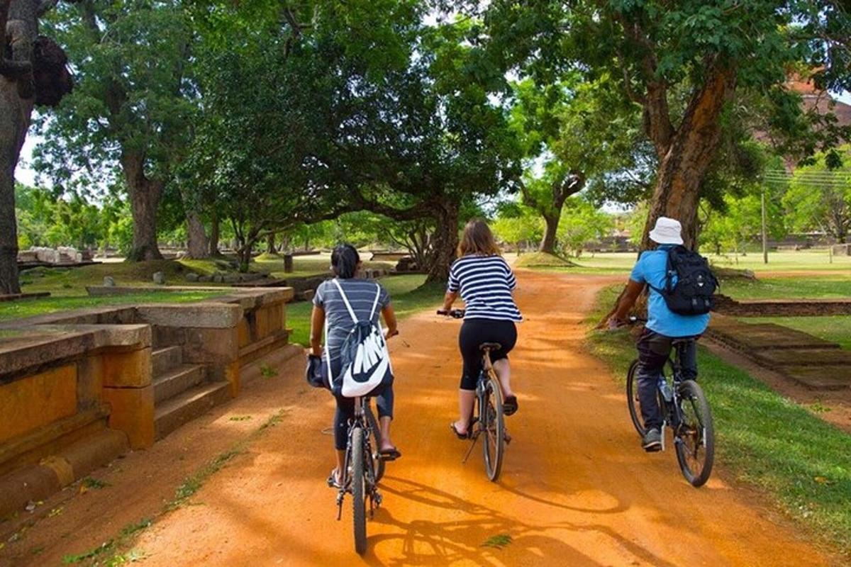 three people riding bikes down a dirt road