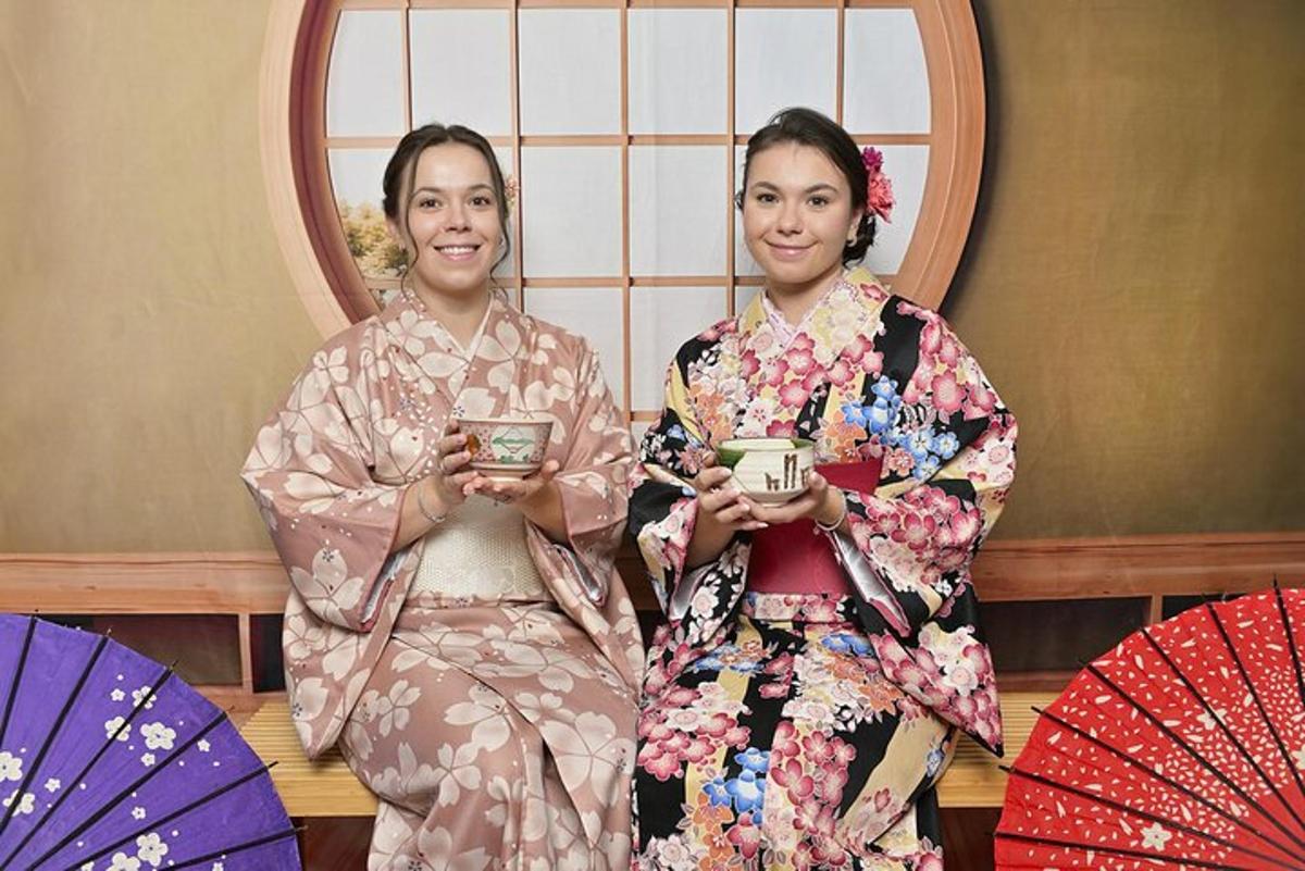two women dressed in kimonos standing in front of a mirror