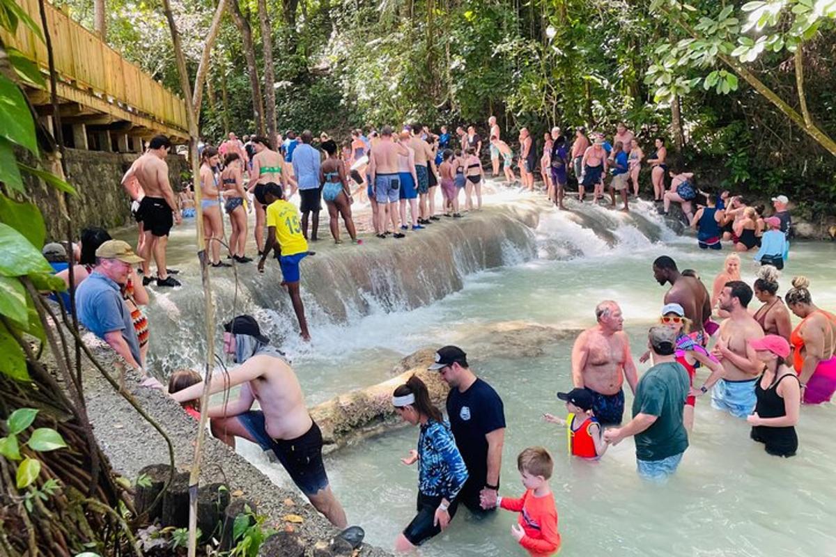 група людей, що стоять у воді біля водоспаду