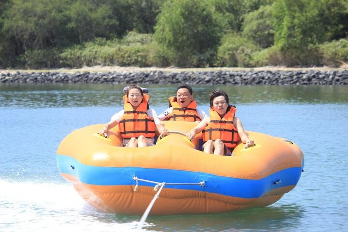 three people sitting on an orange raft in the water