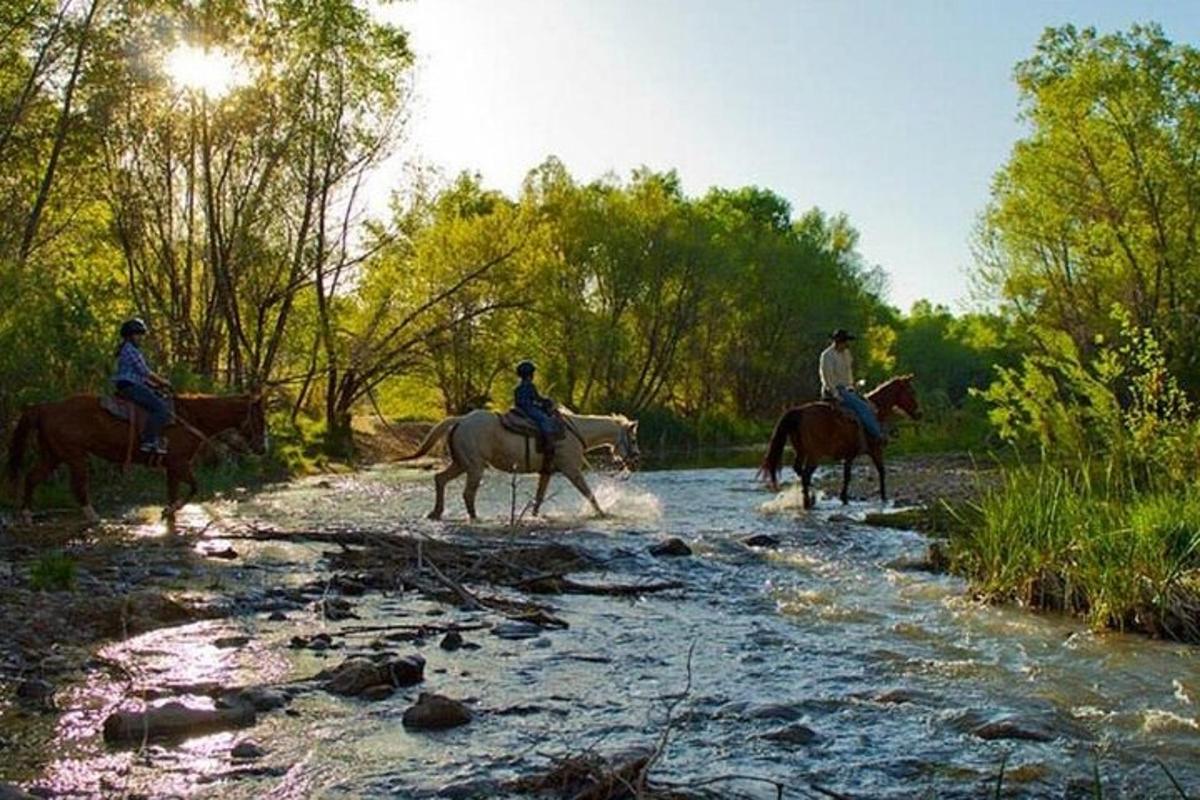 tre persone a cavallo che attraversano un fiume