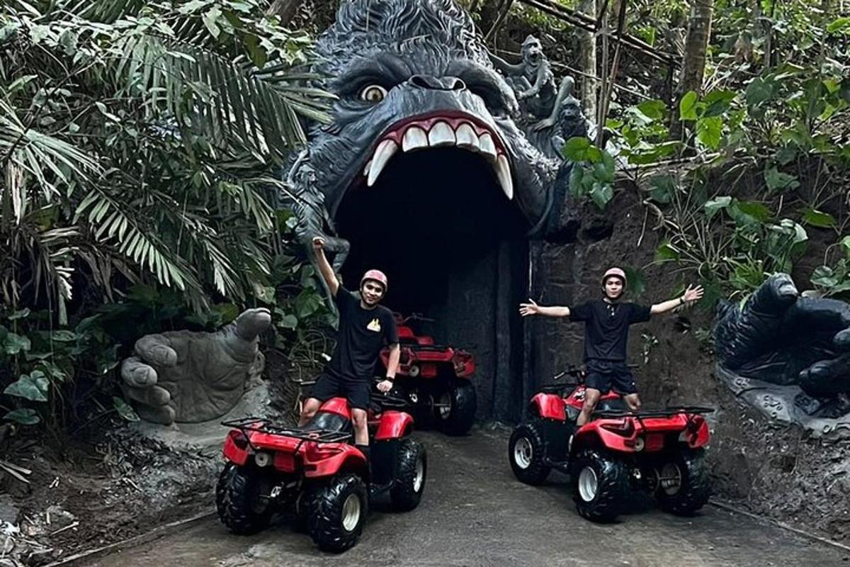 dos homes en quads davant d'un túnel de dinosaures