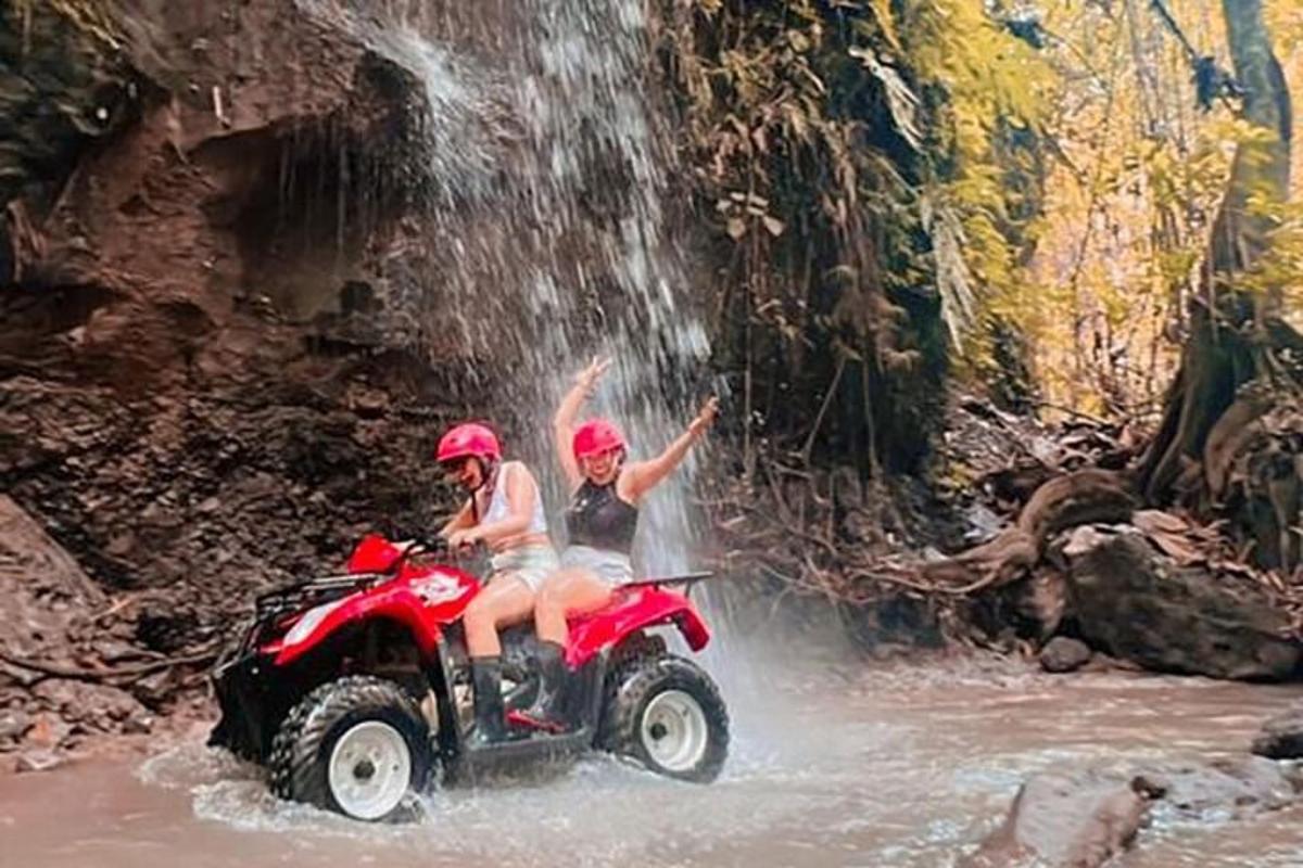 dues persones que viatgen en un quad a través d'una cascada