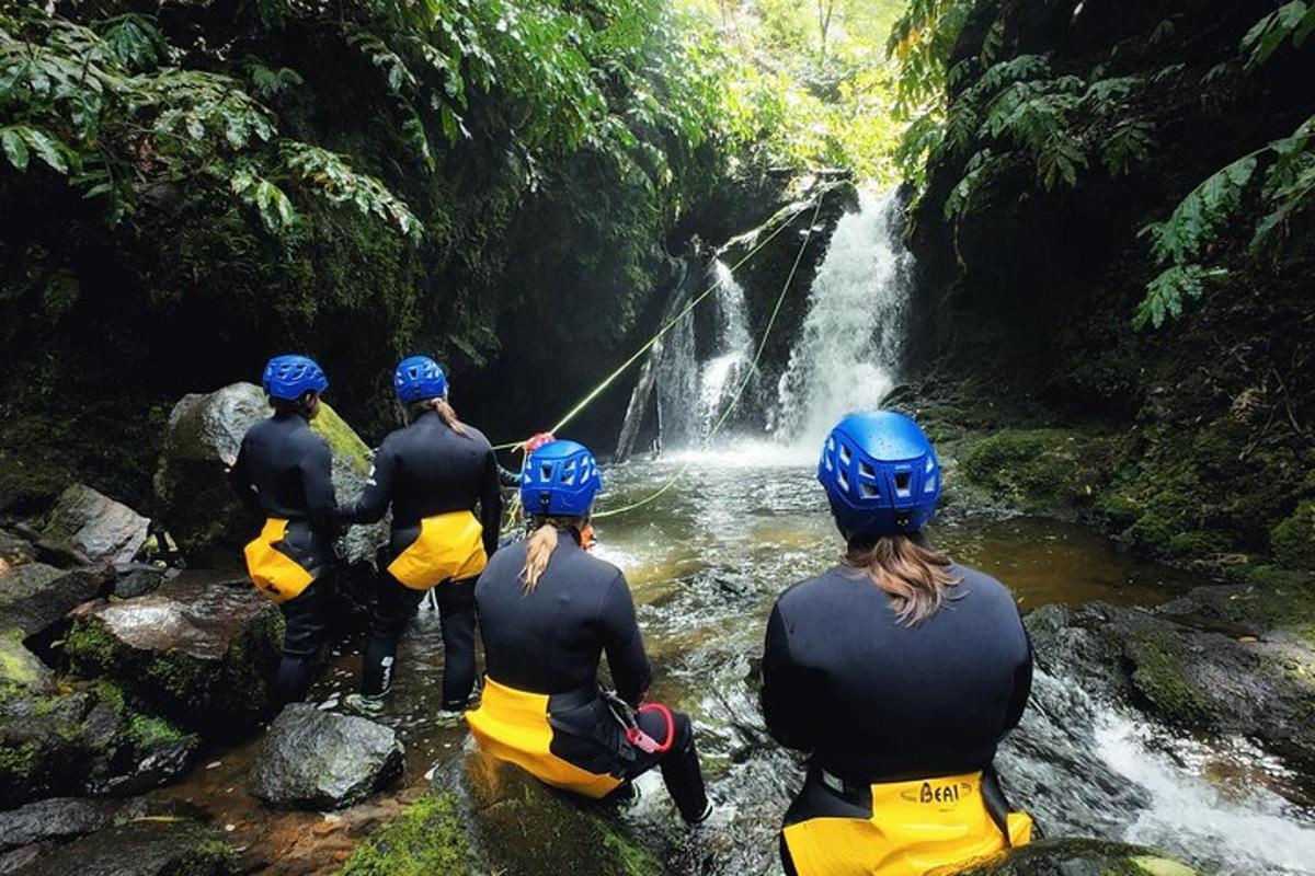 eine Gruppe von Menschen sitzt in einem Fluss in der Nähe eines Wasserfalls