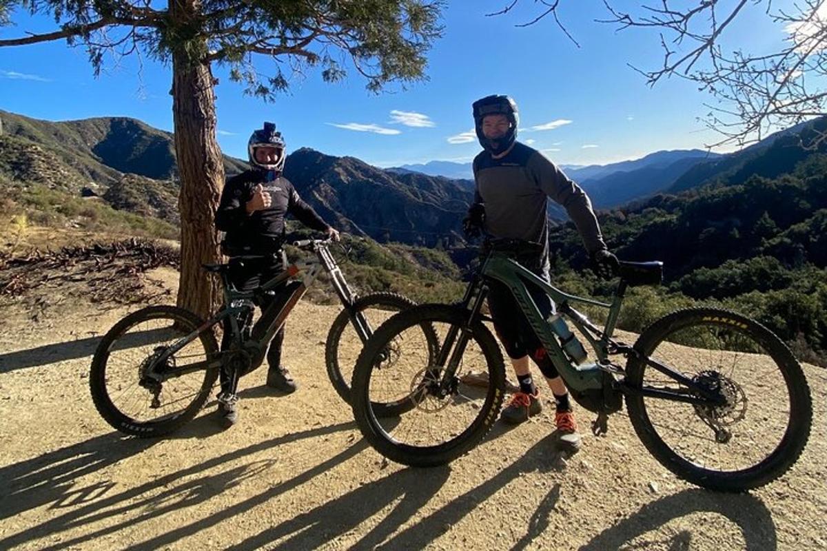 Dos hombres de pie junto a sus bicicletas en una montaña.