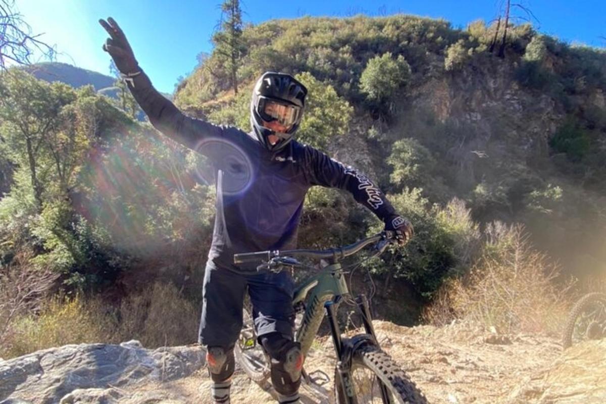 un hombre en bicicleta con la mano en el aire