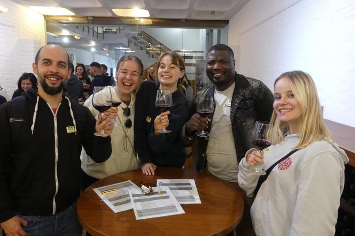 un gruppo di persone in piedi attorno a un tavolo con in mano dei bicchieri di vino