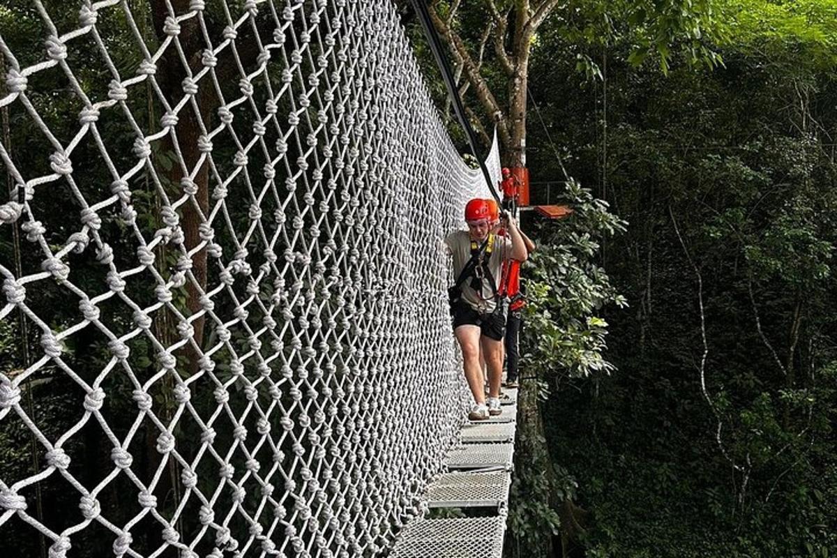 a woman walking on a rope bridge over a white fence