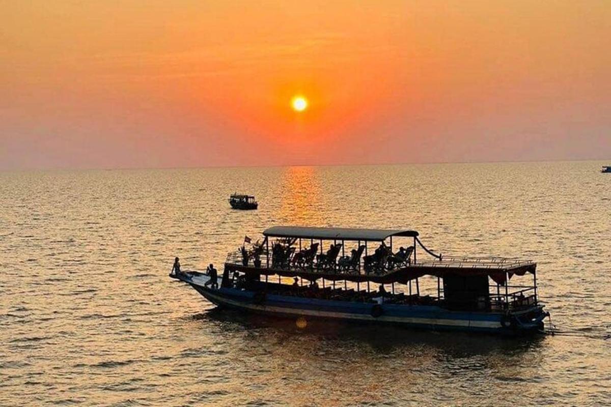 un gruppo di persone su una barca in acqua al tramonto