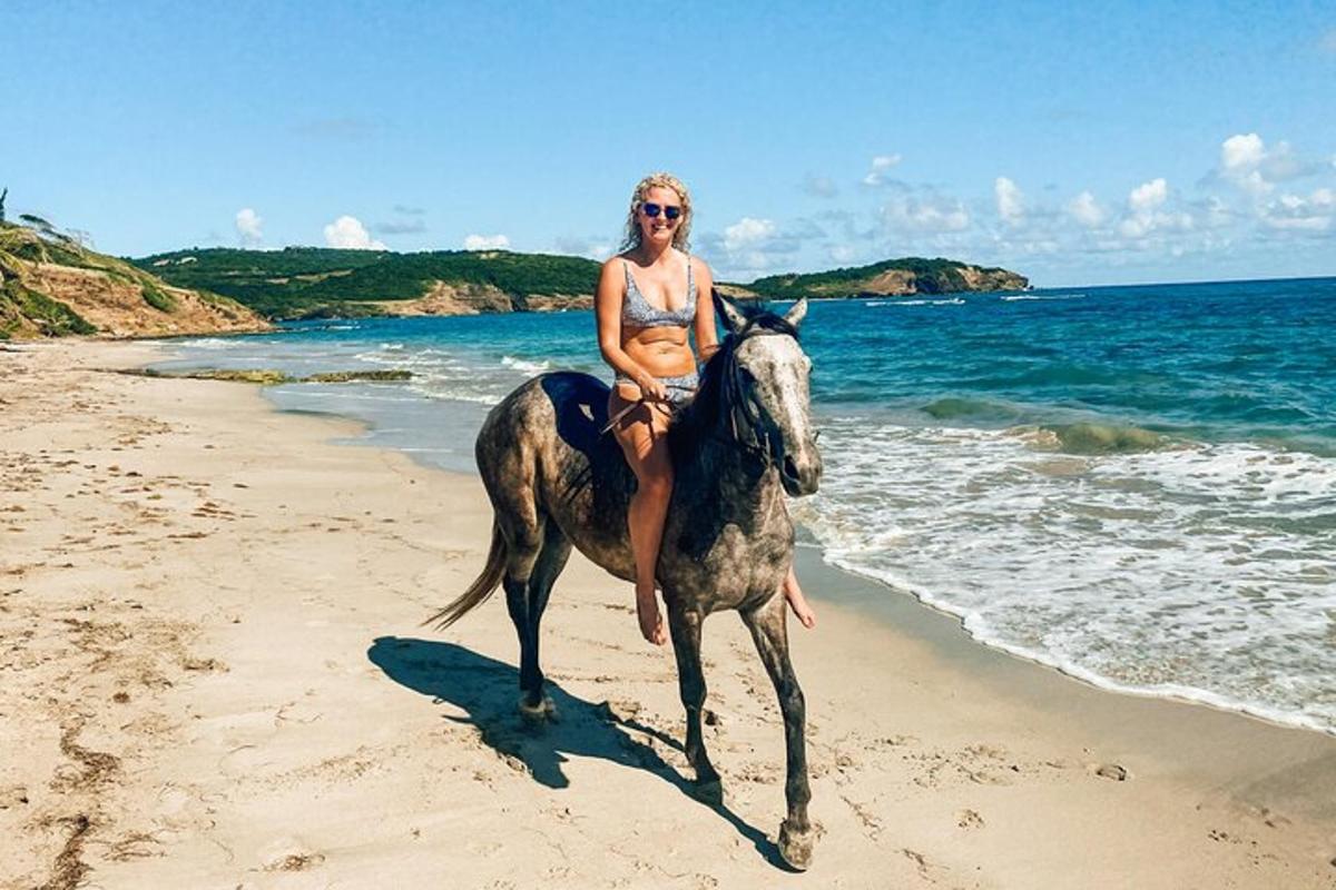 a woman in a bikini riding a horse on the beach