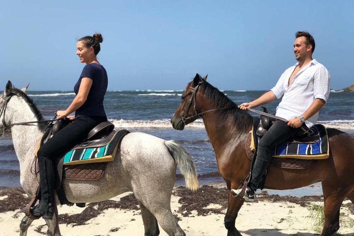 a man and a woman riding horses on the beach