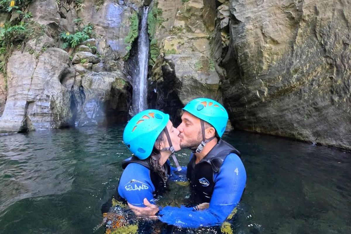 um homem e uma mulher se beijando em frente a uma cachoeira