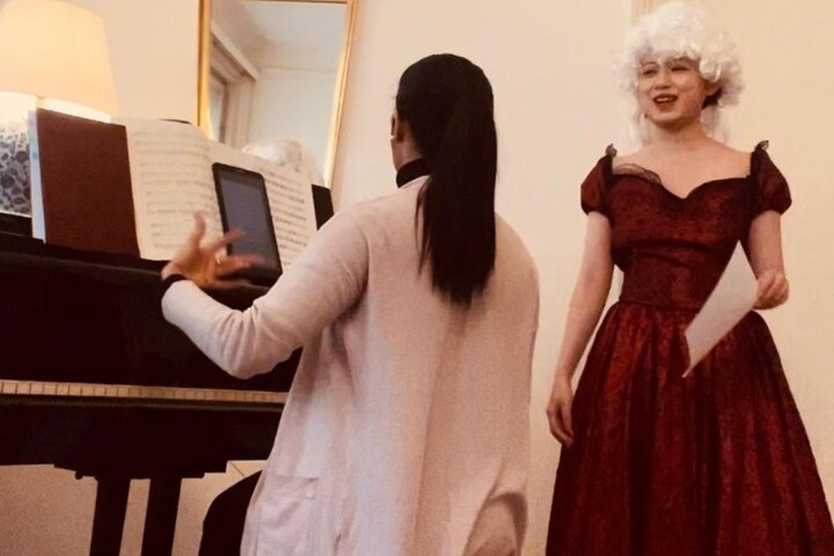 Una mujer parada junto a una mujer frente a un piano