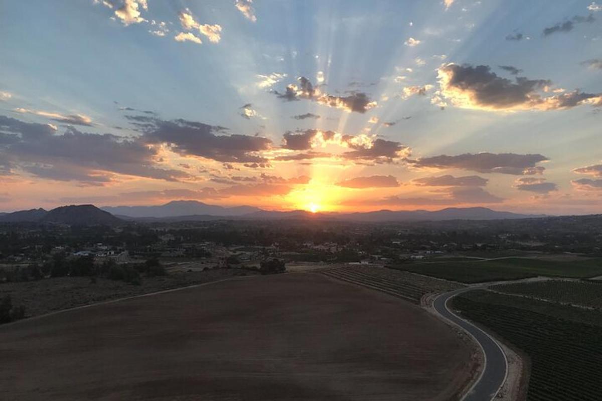 una posta de sol sobre un camp amb el sol al cel