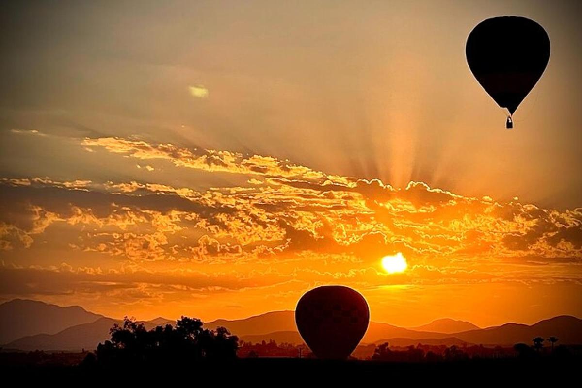dos globus aerostàtics volant a la posta de sol