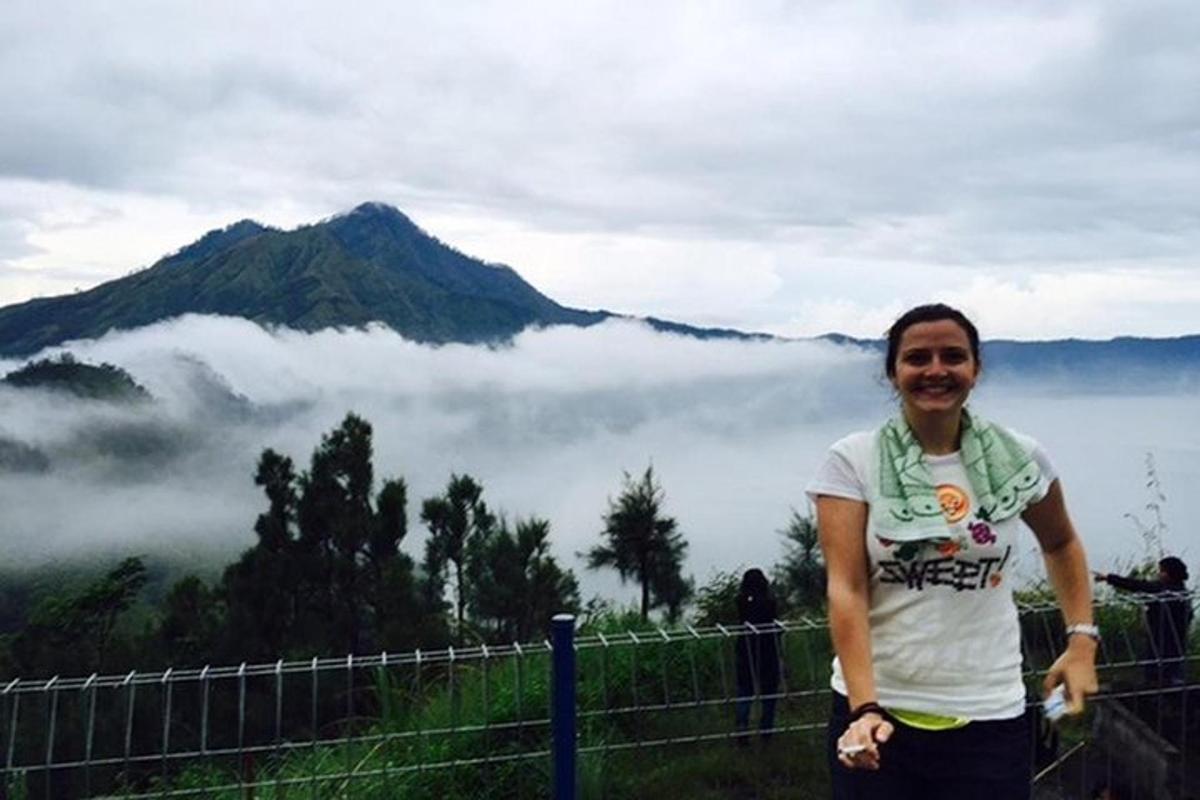 um homem parado em frente a uma montanha com nuvens
