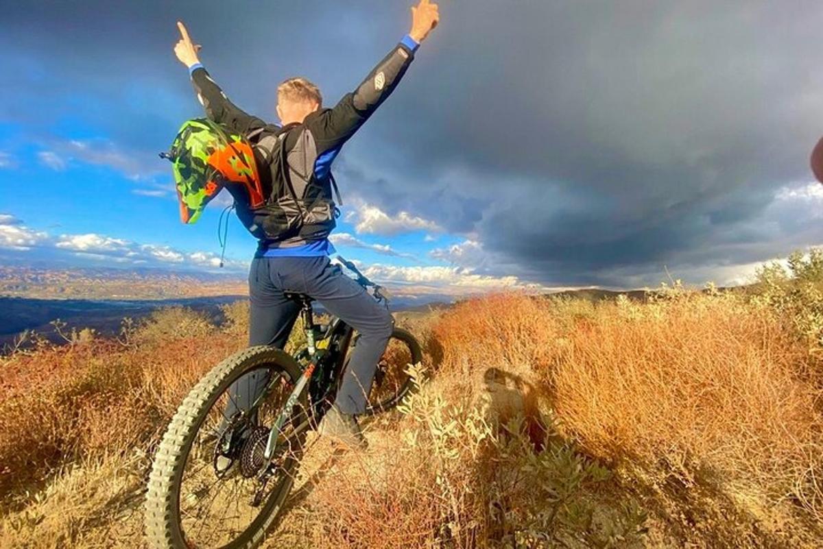 a man riding a bike on a hill with his arms in the air