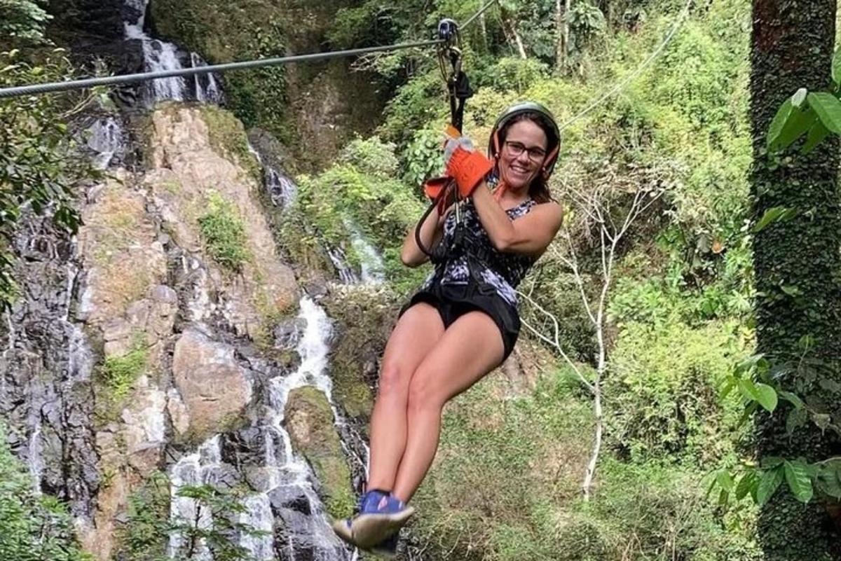 eine Frau auf einer Seilrutsche vor einem Wasserfall