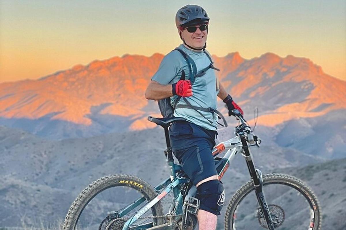 a man standing with his bike on top of a mountain