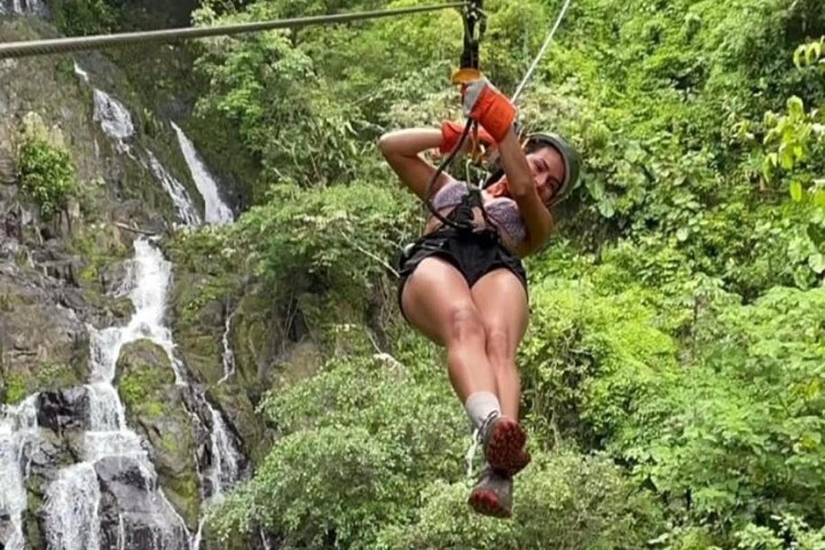een vrouw op een zipline voor een waterval