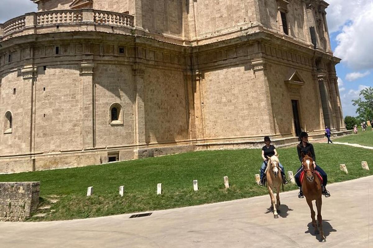 zwei Personen reiten vor einem Schloss