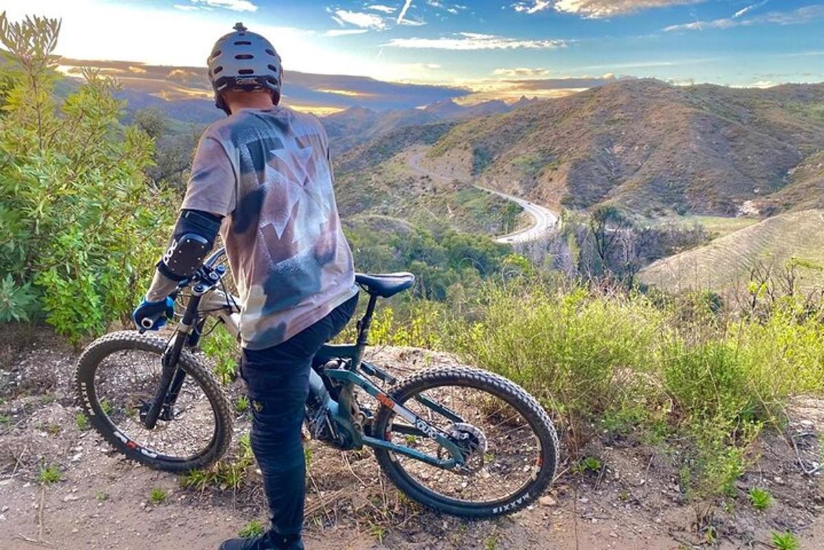 un uomo che tiene una bicicletta in cima a una collina