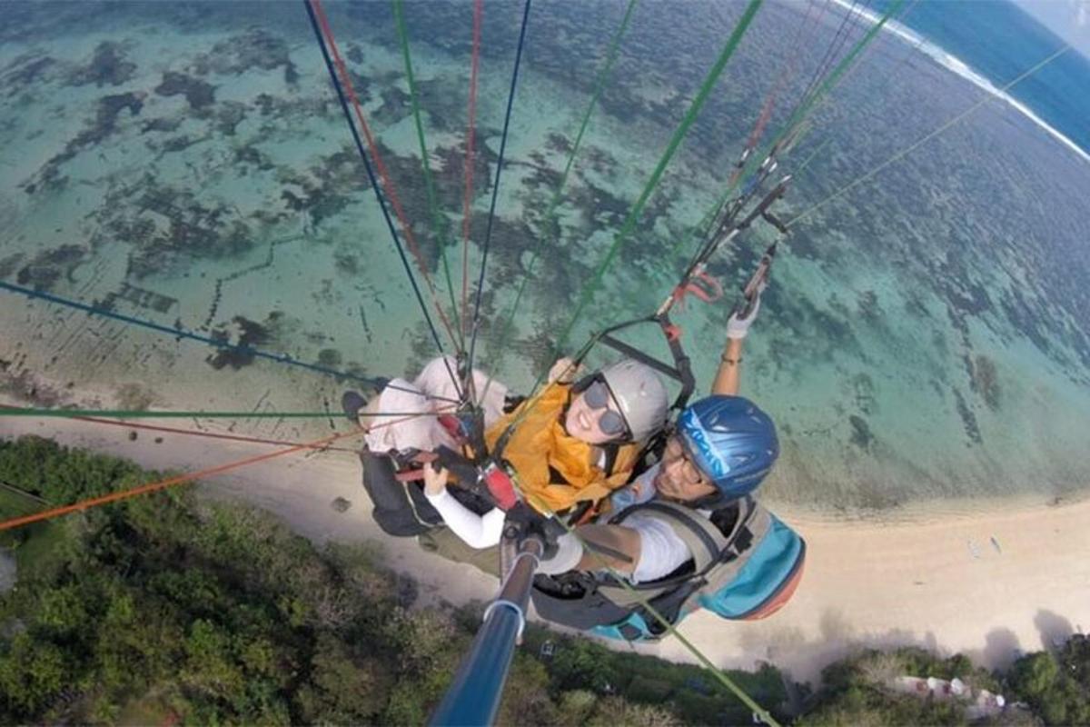 two people are riding on a parachute over the ocean
