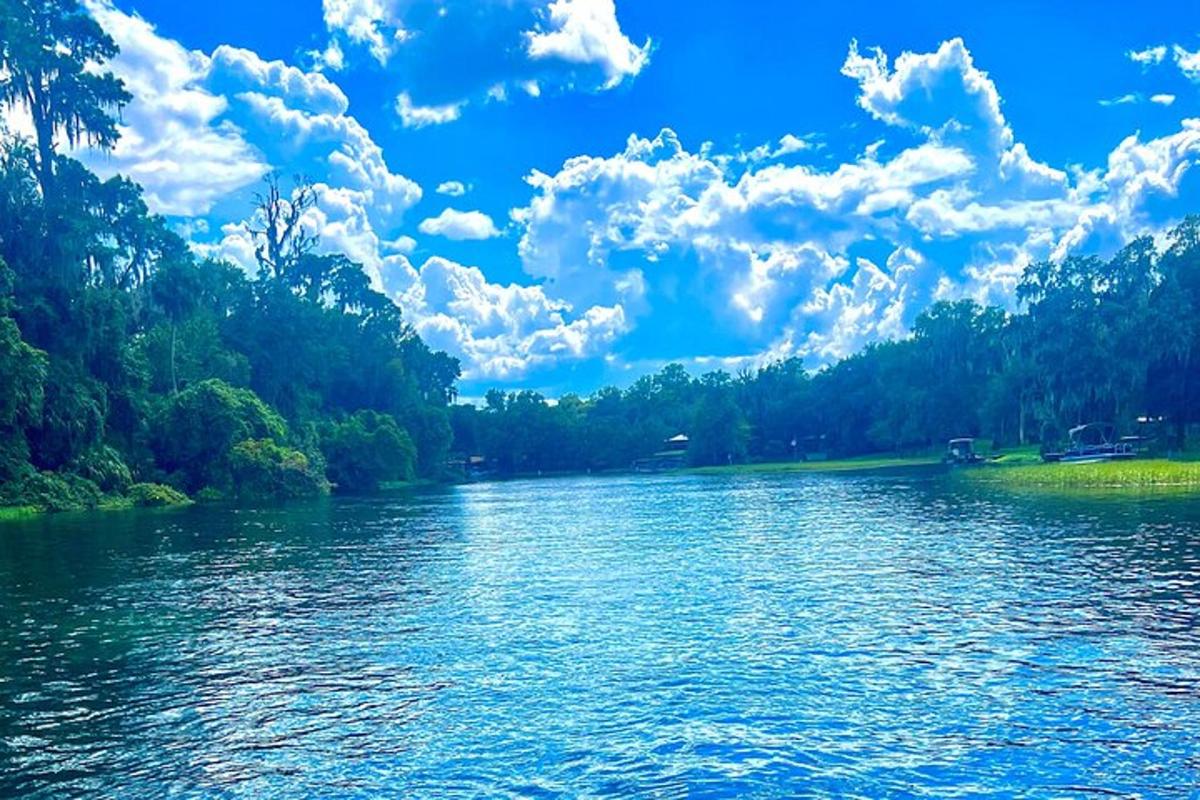 Un río con árboles y nubes en el cielo.