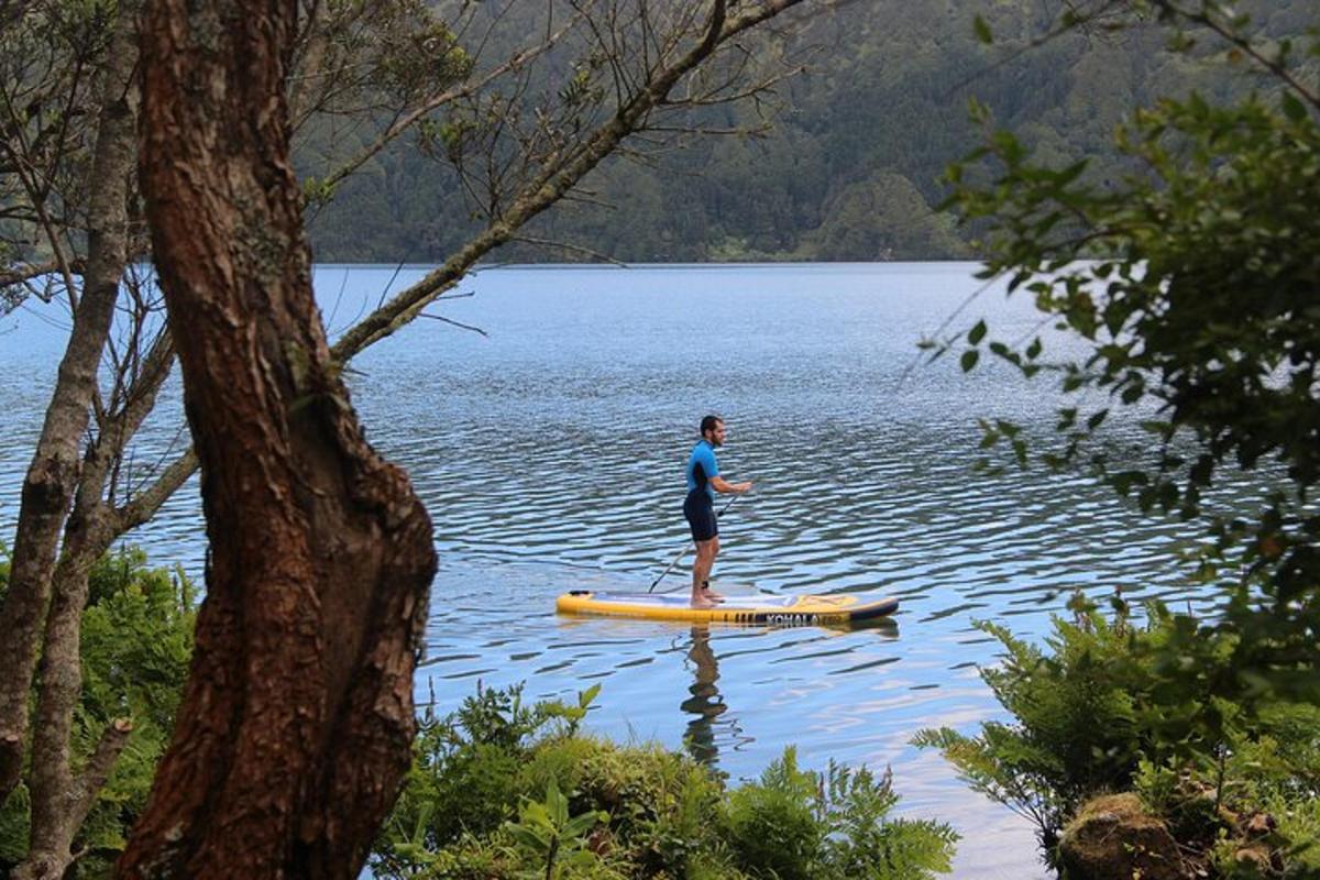 seorang lelaki berdiri di atas papan dayung di tasik