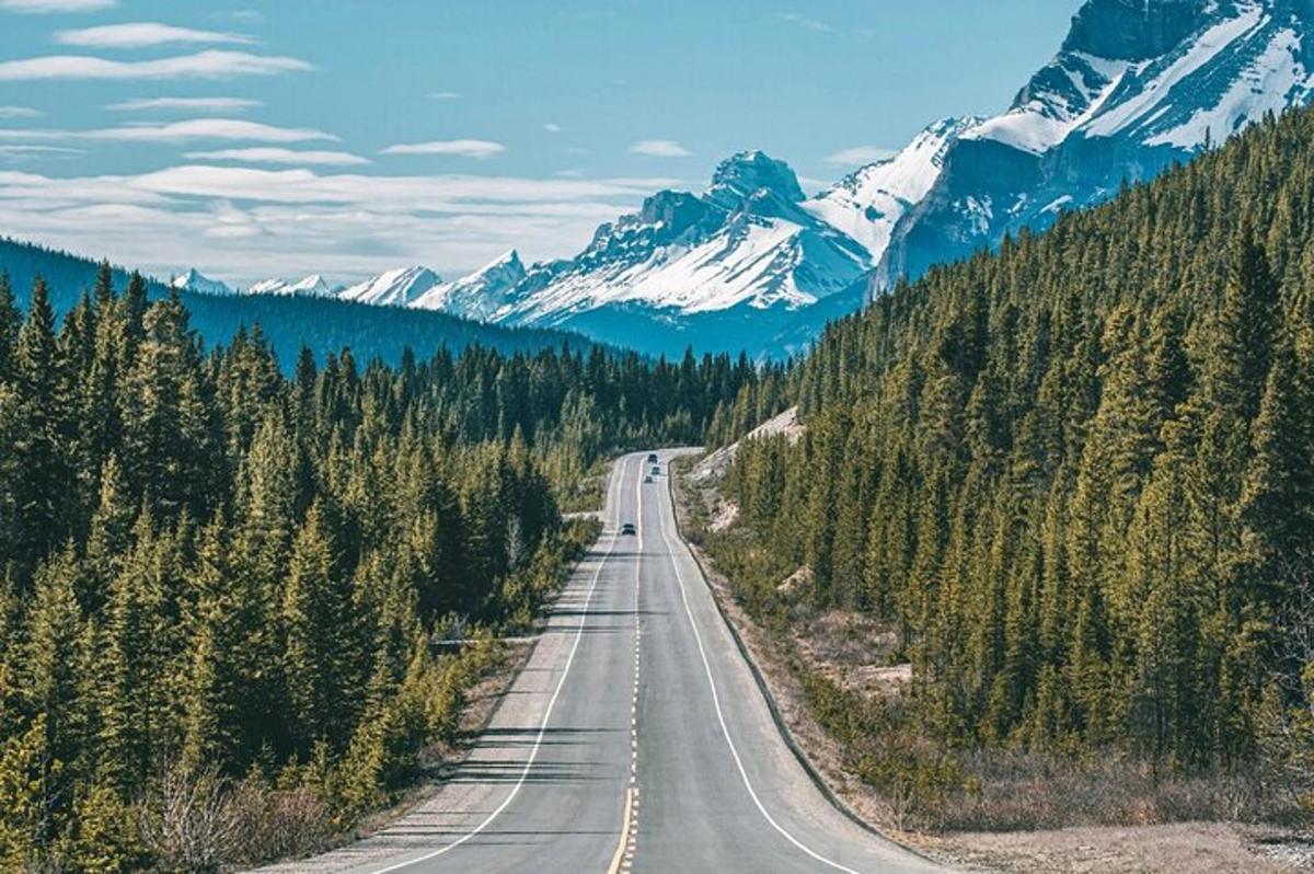 an empty road in the mountains with snow