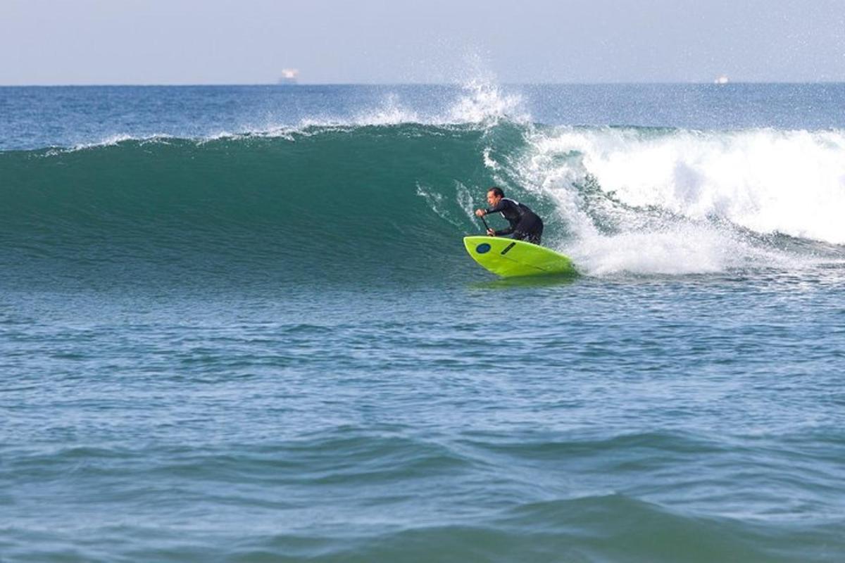 Un hombre montando una ola en una tabla de surf amarilla en el océano.