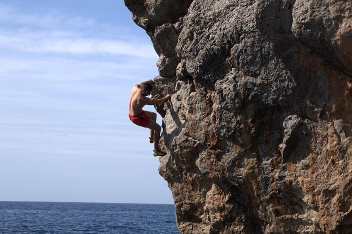 un uomo sta scalando una roccia nell'oceano