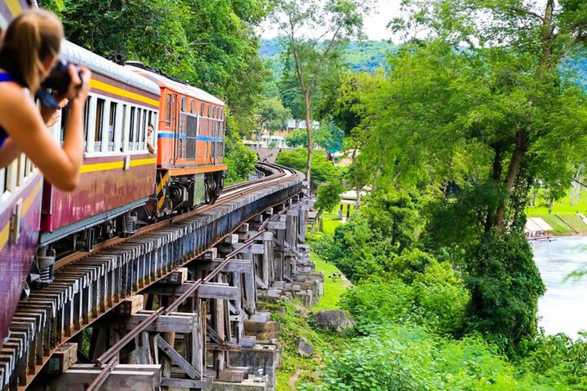 una persona che scatta una foto di un treno che attraversa un ponte