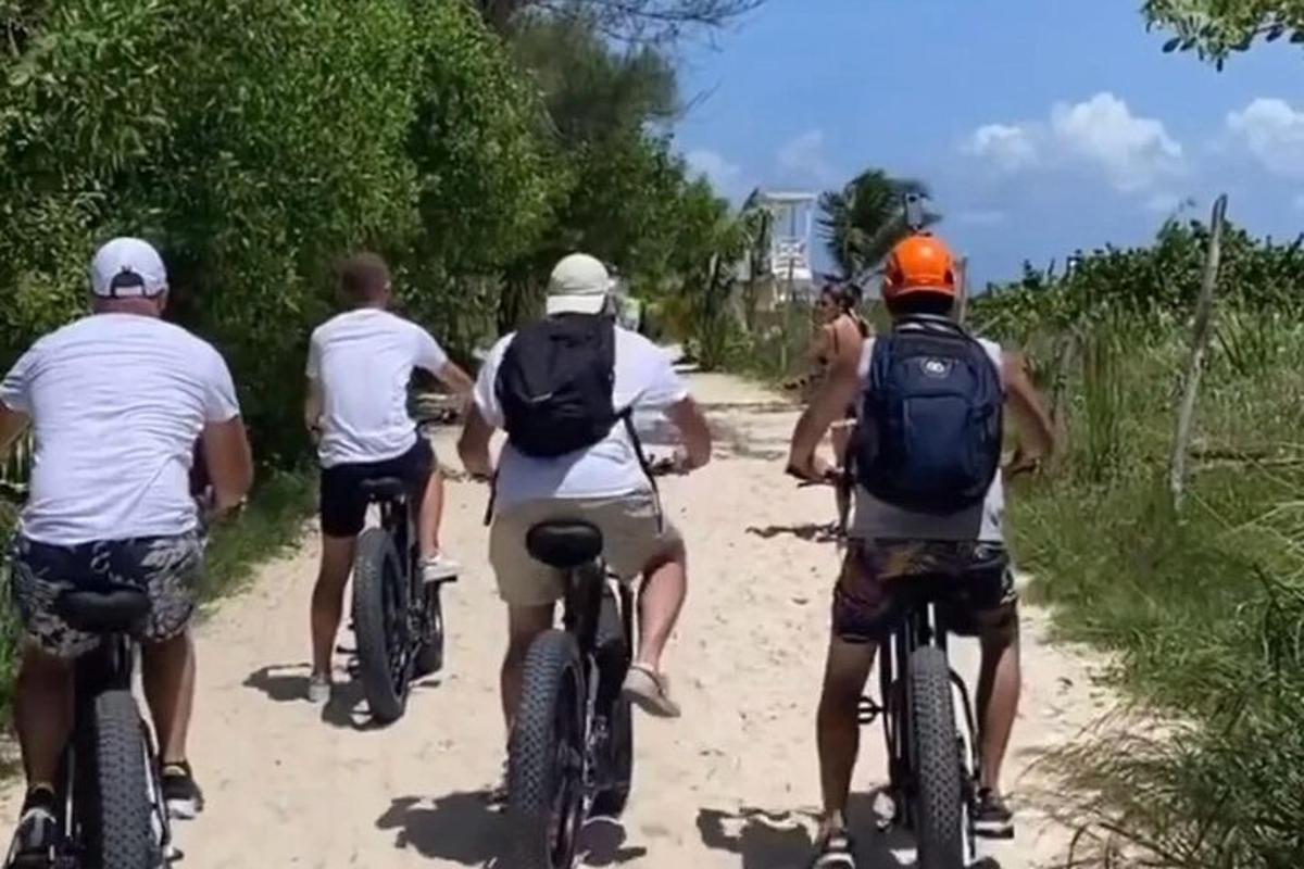 cilvēku grupa, kas brauc ar velosipēdiem pa netīru ceļu